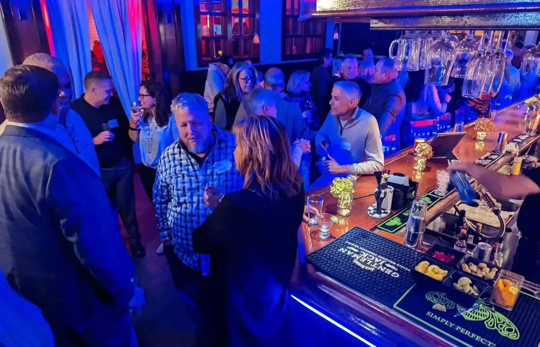 A busy bar at Midtown Social with guests along the rail and bartenders working under blue lighting.