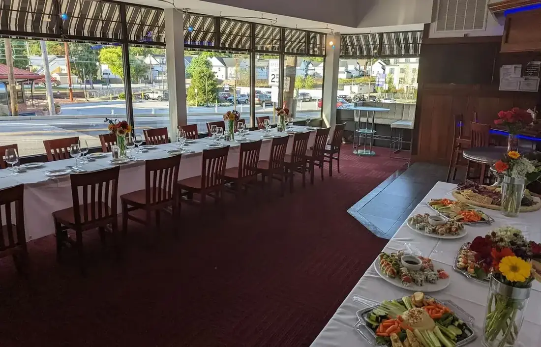 The first floor at Midtown Social set for a daytime event, a long table dressed by the windows with Lancaster Avenue and Berwyn station outside.