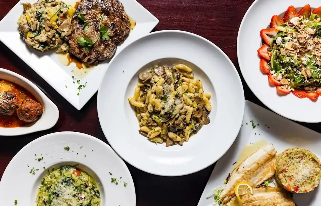 A spread of dishes at Midtown Social — ribeye with mushroom risotto, cavatelli with wild mushrooms, strawberry salad, meatballs and a plated fish course.