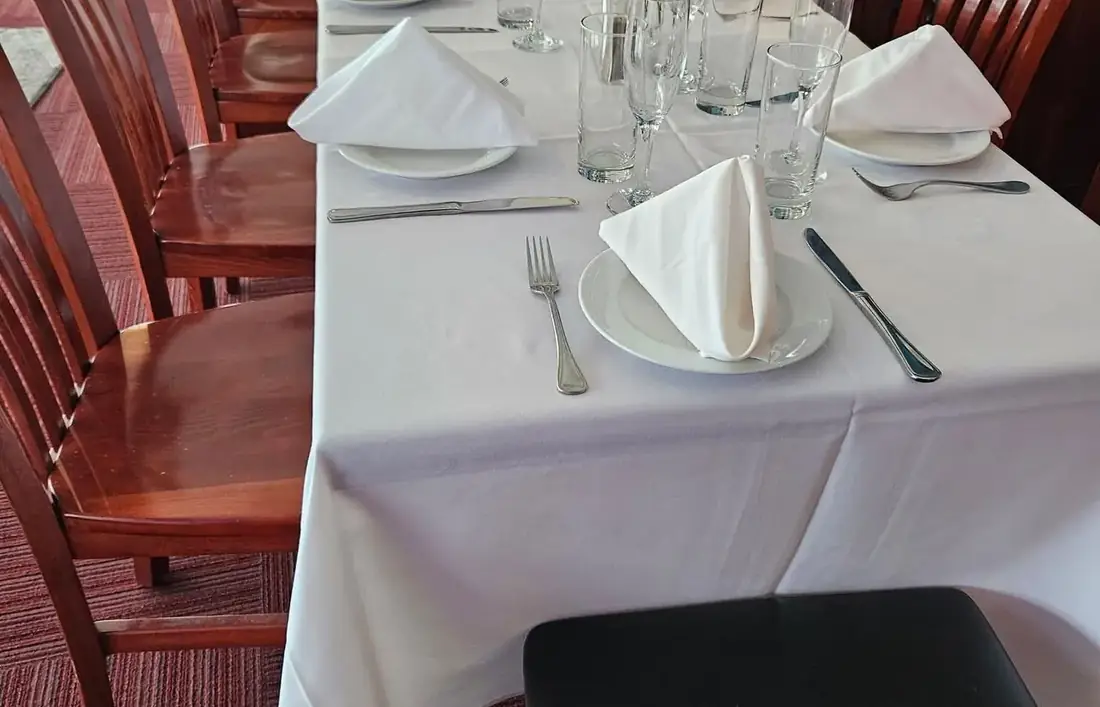 A long table set with white linen, glassware and fresh flowers on the first floor at Midtown Social.