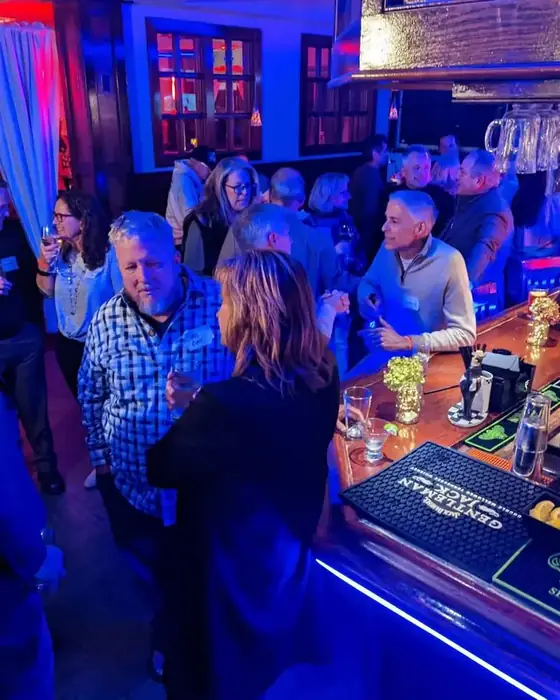 Guests standing along the bar at Midtown Social under blue lighting during a busy evening.