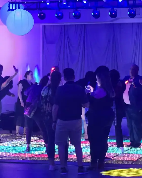 A full dance floor in Midtown Hall, guests dancing on illuminated floor panels.
