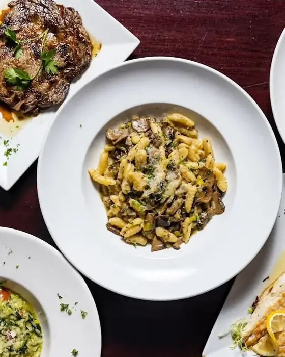 A spread of dishes at Midtown Social — a grilled ribeye, fresh pasta, a salad and meatballs.