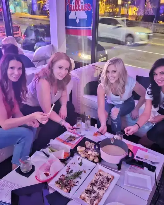 Four friends on a white sofa sharing fondue and flatbreads at Midtown Social.