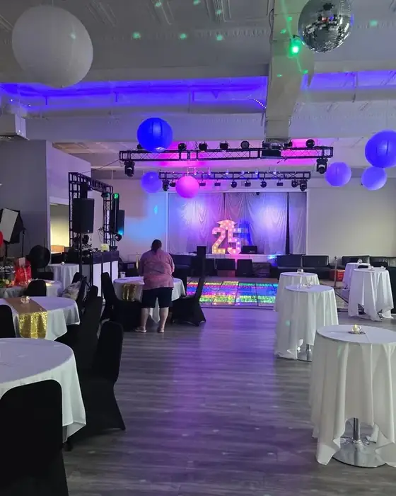 Midtown Hall set for a graduation party with cocktail tables, an illuminated dance floor and truss lighting.