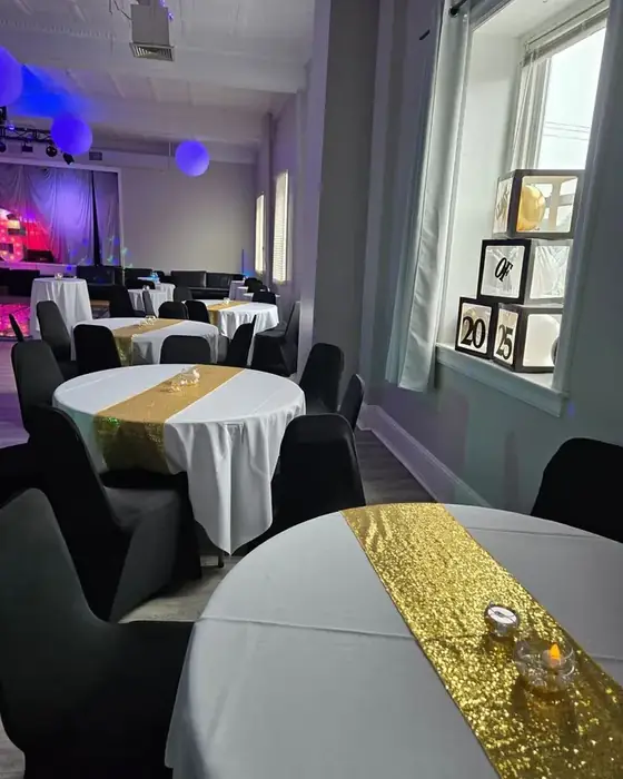 Round tables with white linen and gold sequin runners set in Midtown Hall beside the dance floor.
