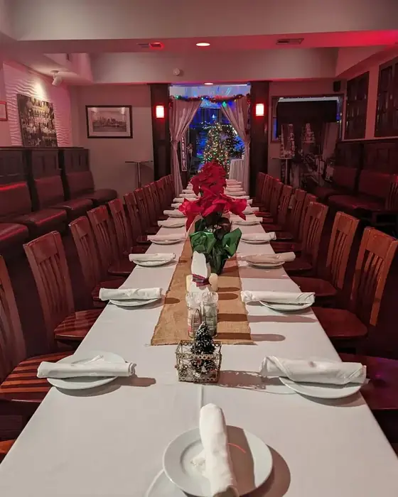 A long table set for a holiday party with white linen, poinsettias and Christmas lights on the first floor.