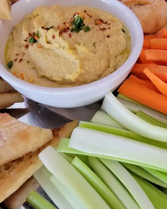 A platter of hummus with warm pita, carrot and celery sticks from the catering menu.