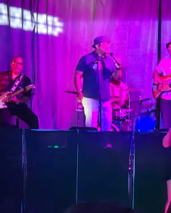 A live band on the stage in Midtown Hall lit purple, with the crowd watching from the floor.