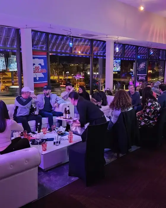 The first floor lounge full of guests on white sofas, big screens showing sport, Phillies and Eagles flags in the windows.