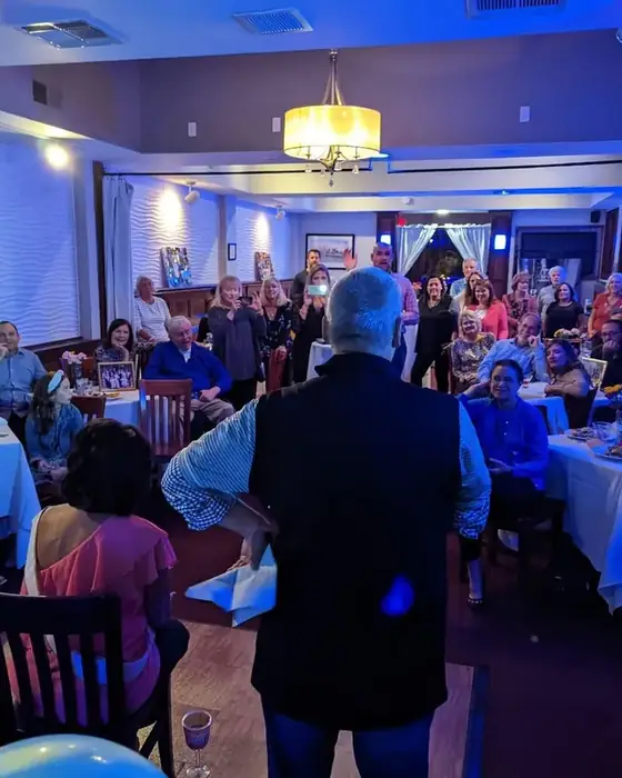 A host addressing a seated crowd at a private party on the first floor at Midtown Social.
