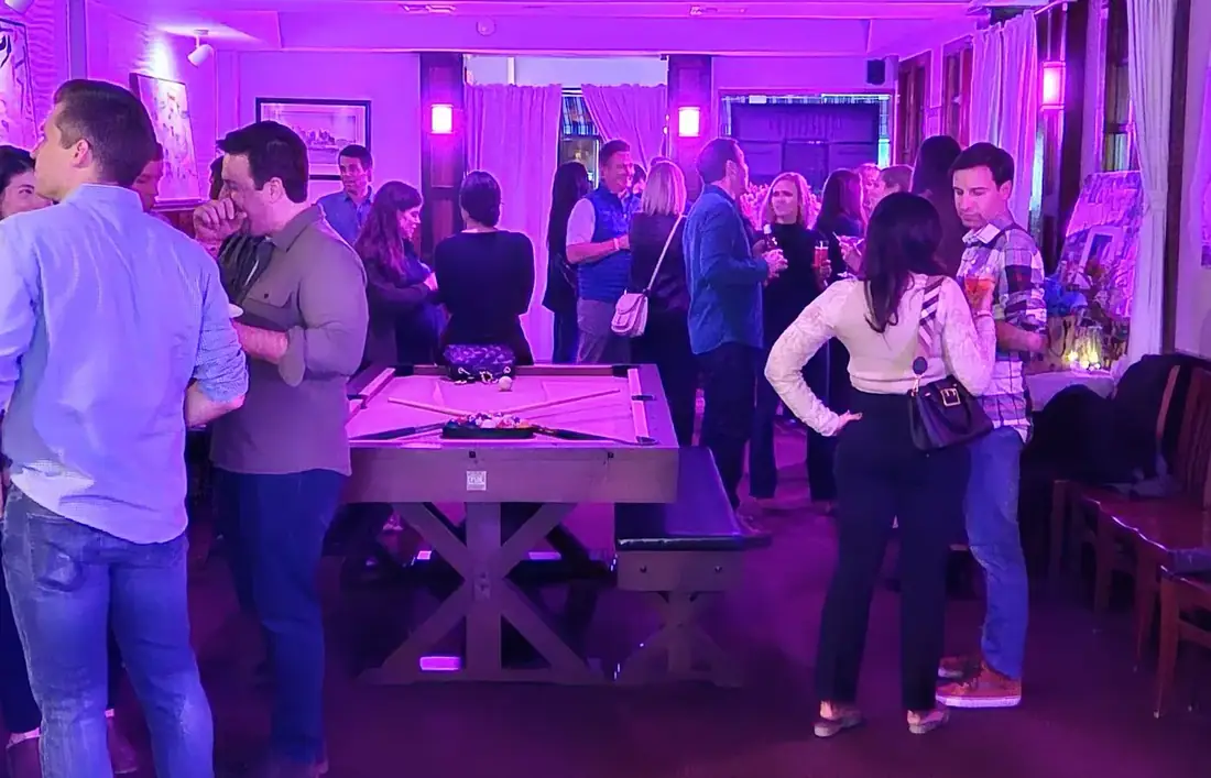A crowd standing around the pool table in the front room at Midtown Social during a party.