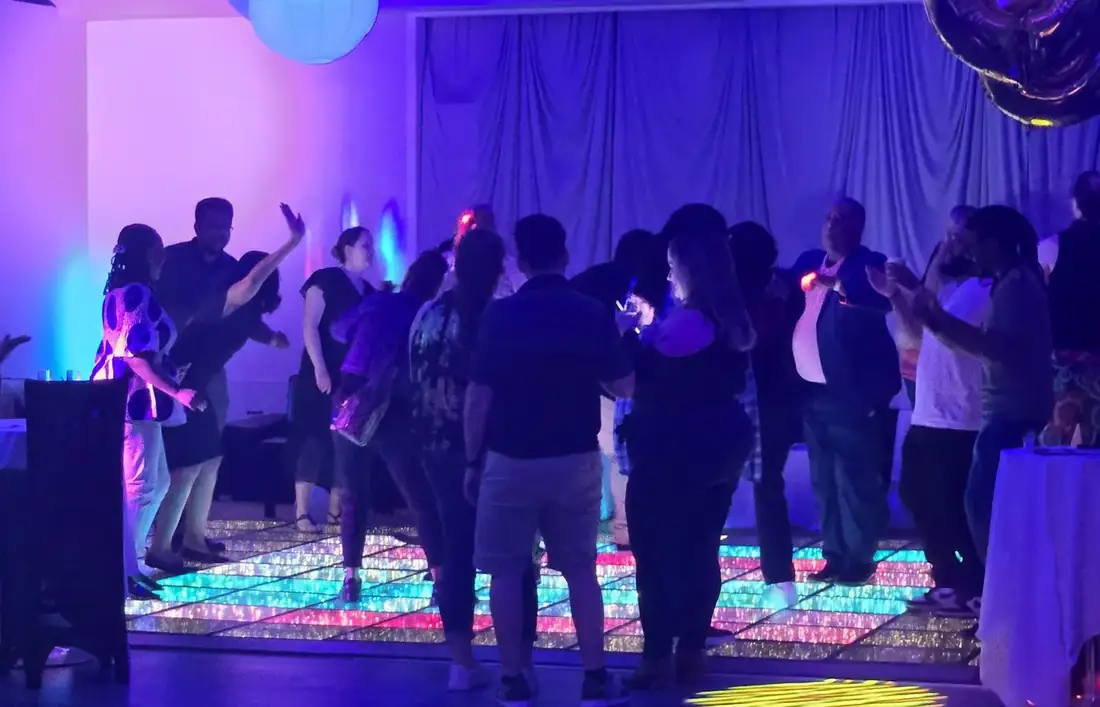 Guests dancing on the lit LED dance floor in Midtown Hall under blue stage lighting.