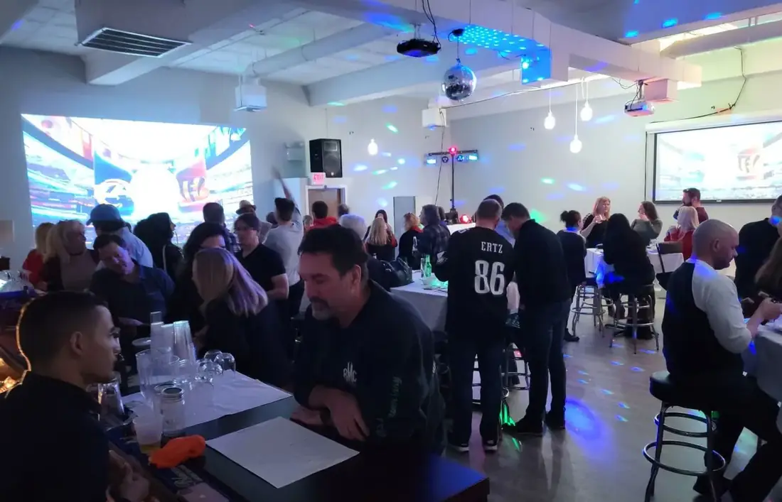 A watch party in Midtown Hall with football on two large projection screens, a crowd standing at high tables and its own bar.