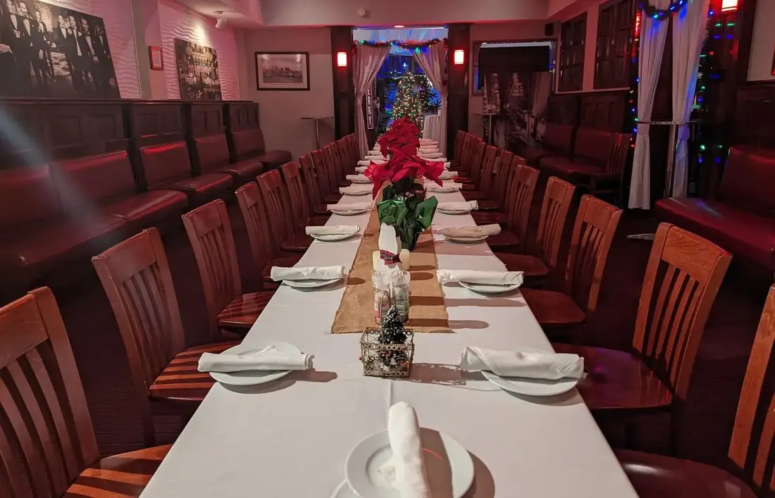 A long table set for a holiday party on the first floor at Midtown Social, with white linen and poinsettias.