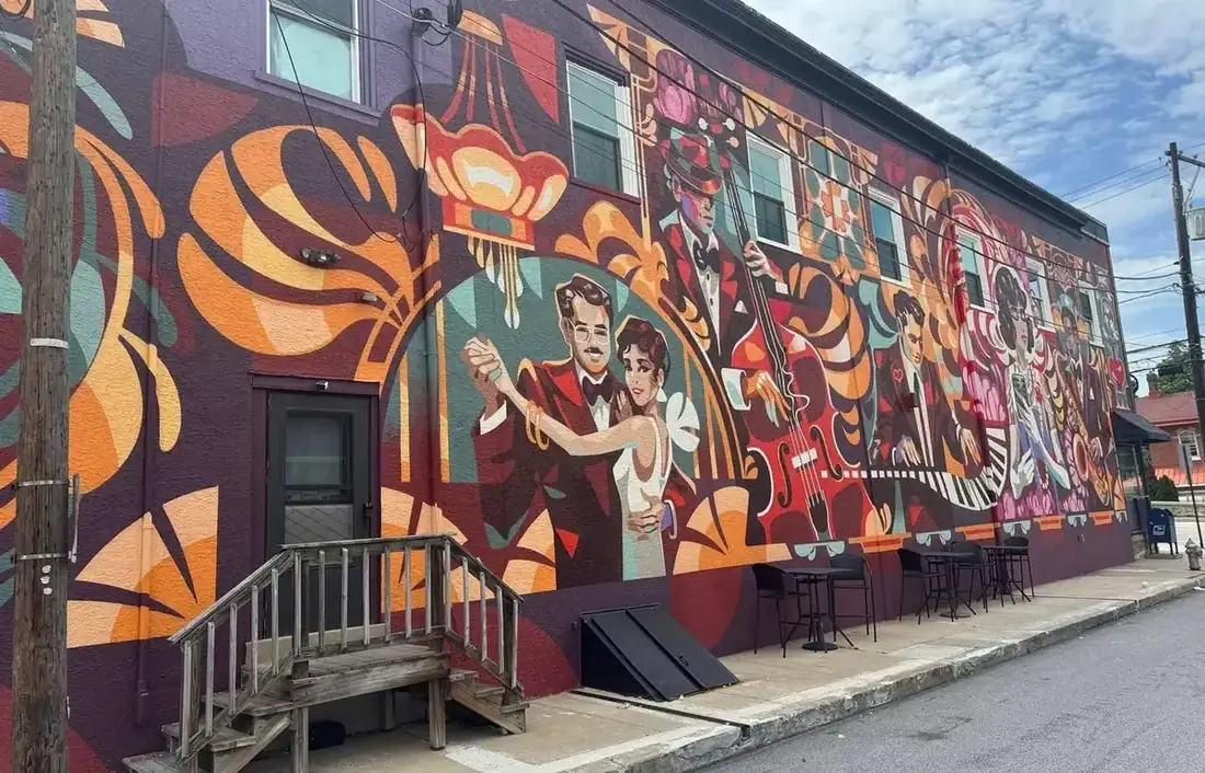 A closer view of the Berwyn mural showing the dancing couple and the double bass player, painted in deep reds, oranges and teal.