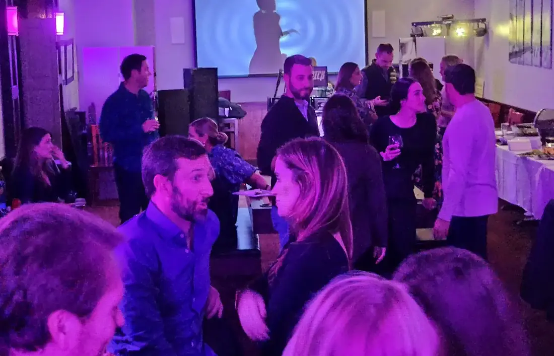 A busy night at Midtown Social with a DJ playing, projection on the wall and a full room of guests.